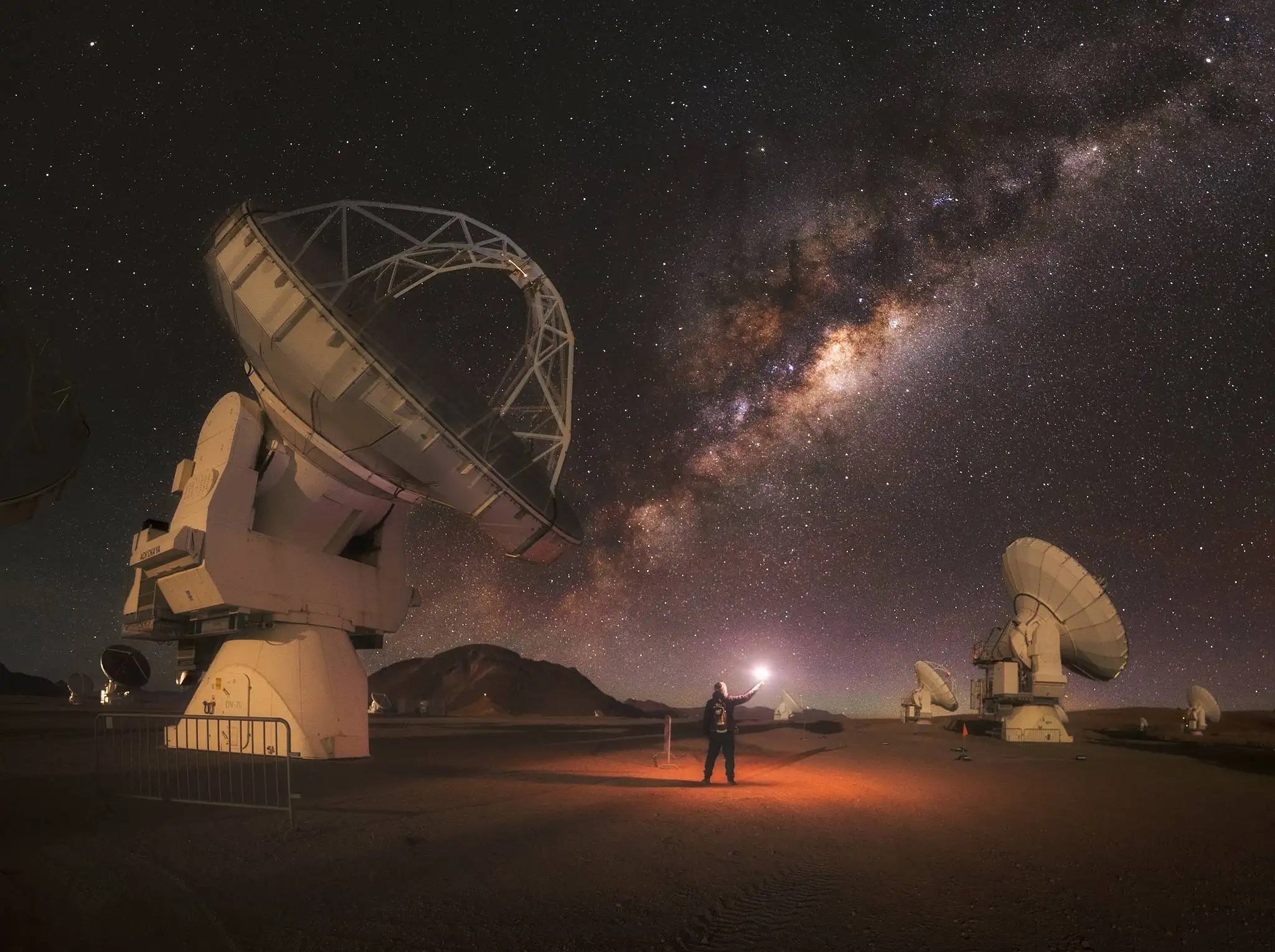 Fotógrafo señalando el núcleo galáctico de la Vía Láctea sobre las antenas del Observatorio ALMA en el altiplano atacameño, mayo-junio, San Pedro de Atacama