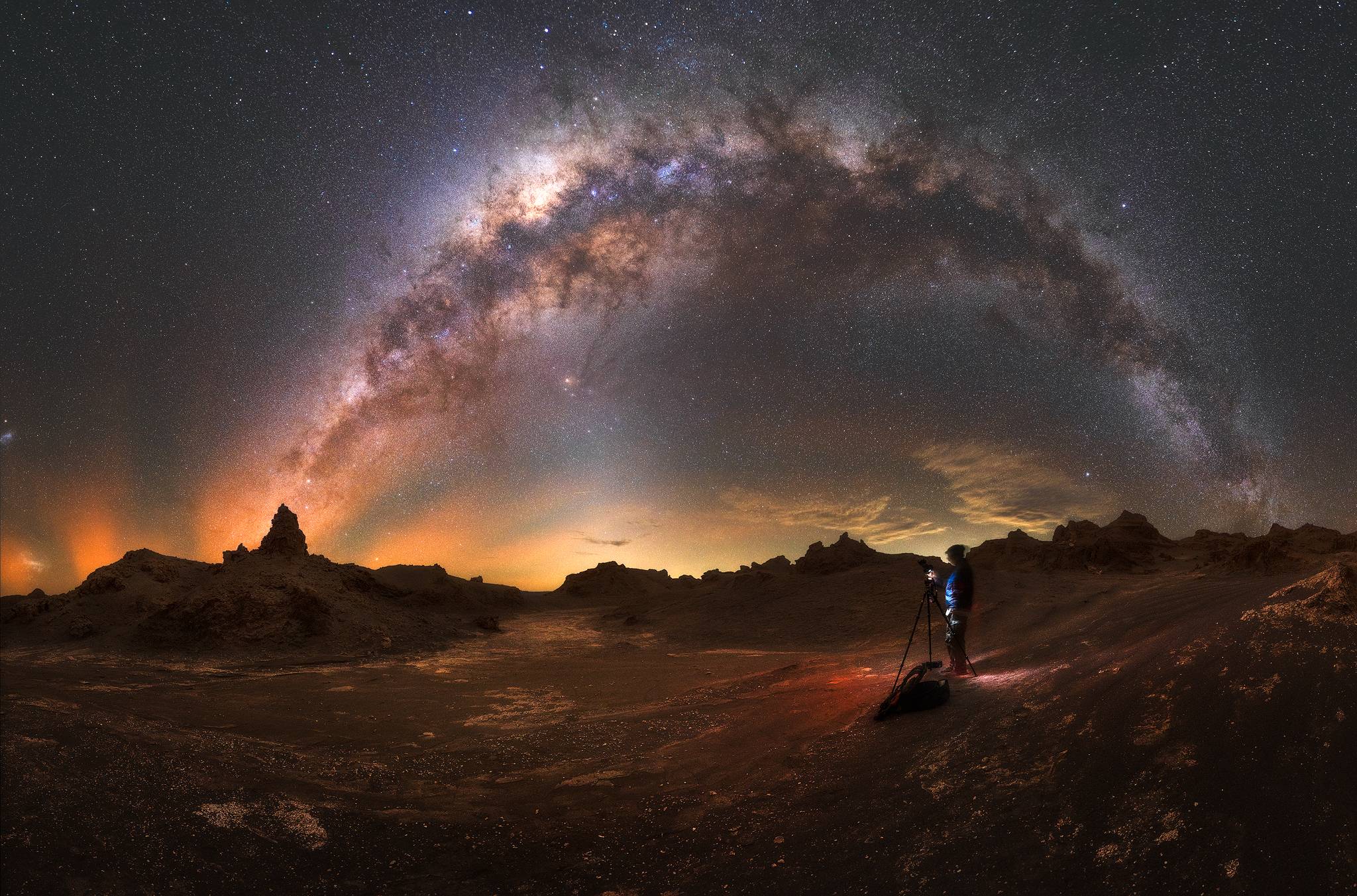 Fotógrafo capturando el arco completo de la Vía Láctea sobre formaciones rocosas del desierto de Atacama, Chile